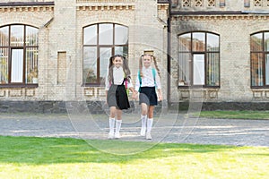 two schoolkids in uniform walking together outdoor