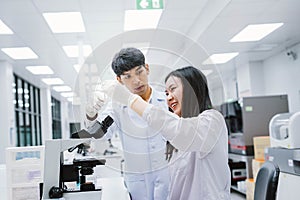 Two  scientist looking at test tube in medical laboratory , select focus on male scientist