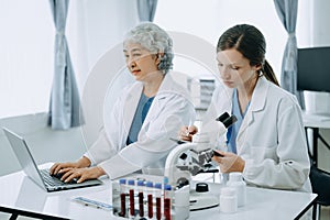 Two scientist or medical technician working, having a medical discuss meeting with an Asian senior female scientist supervisor in