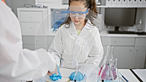 Two scientists in safety glasses engrossed in medical research, meticulously taking notes at the lab, indoor