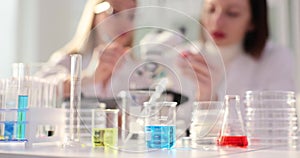 Two scientists working in a laboratory with colored liquids and a microscope