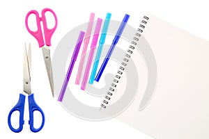 Two scissors, five felt tip pens in pink, blue and purple colors and blank sketchbook, isolated on white background. Space for tex