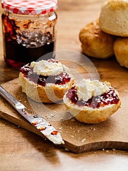 Two scones prepared with clotted cream and jam photo