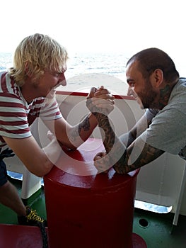 Two seamen are arm wrestling on board of a vessel at sea photo