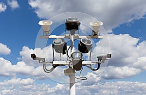Two security cameras, floodlights and loudspeakers against the blue sky