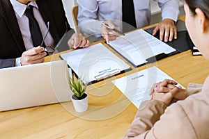 Two selection committee manager reading a resume during a job interview, Employer interviewing to ask young female job seeker for