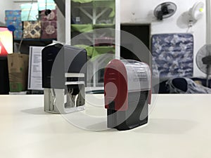 Two self inked printer dater on top of a beige desktop in the workplace