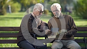 Two senior brothers looking at photo and remembering relatives, memories