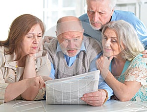 Senior couples reading newspaper