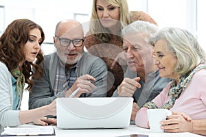 Two senior couples talking with consultant while sitting at table