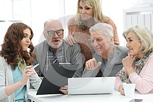 Two senior couples talking with consultant while sitting at table