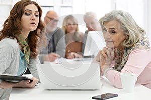 Two senior couples talking with consultant while sitting at table