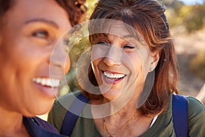 Two Senior Female Friends Hiking Along Trail In Countryside Together