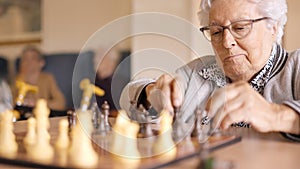 Two senior friends playing chess board game in geriatric