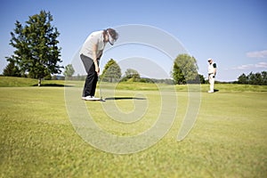 Two senior golf player on green.