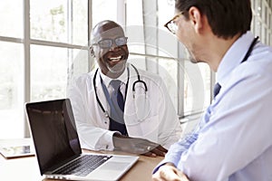 Two senior healthcare workers in consultation laughing