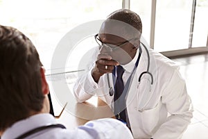 Two senior healthcare workers in consultation, over shoulder