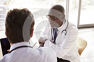 Two senior healthcare workers in consultation, over shoulder