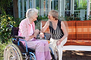 Two senior ladies chatting on a garden bench.