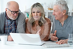 two senior men and woman sitting at table