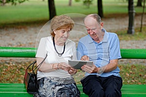 Two senior people sitting with a tablet PC
