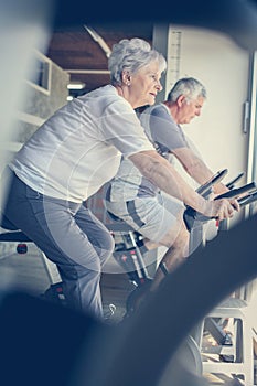 Two senior people working out on elliptical machine.