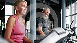 Two senior people working out on elliptical machine