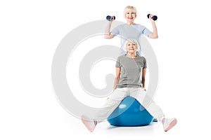 Two senior sportswomen with fitness ball and dumbbells