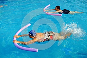 Two senior women doing swimming exercise in pool.