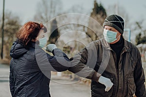 Two seniors wearing facial masks and gloves greeting with hand sign