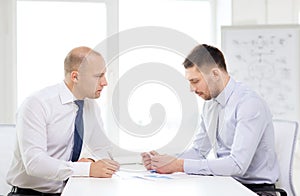 Two serious businessman with papers in office