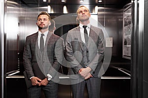 Two serious businessmen met in the elevator, waiting to get out of there