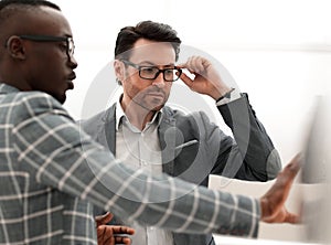 Two serious businessmen talking standing in the office