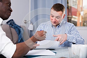 Two serious men analysing documents at home