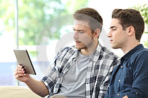 Two serious men checking tablet content at home