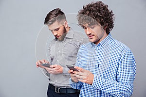 Two serious men using smartphone