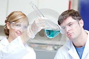 Two serious scientists looking at a blue liquid