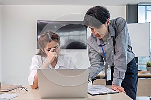 Two serious and stressed Asian office workers are focusing on their co-project together, planning and finding solutions