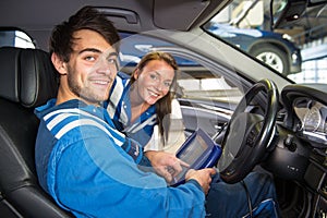 Two service mechanics, running a diagnostics program inside a vehicle