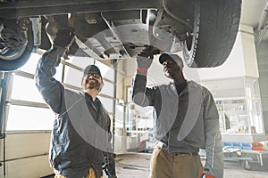 two servicemen working on a car using special tools, medium shot car workshop