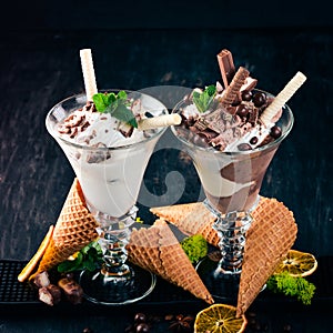 Two servings of ice cream. On a black wooden background.