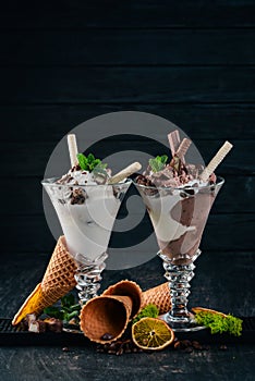 Two servings of ice cream. On a black wooden background.