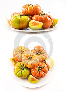 Two sets of compositions of lycopersicum type tomatoes on a white plate photo