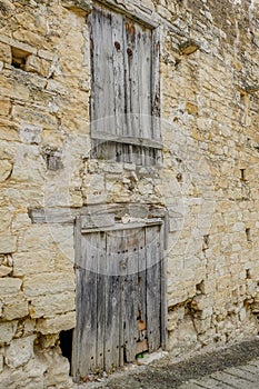 Two sets of very old wooden doors in a stone wall.