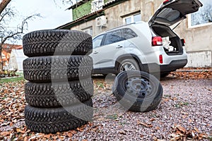 Two sets of winter wheels and tyres ready for replacement at car, copyspace