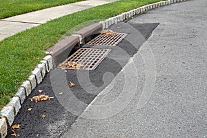 Two sewer grates on an asphalt street that has been repaired