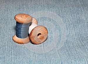 Two sewing spools with colorful threads lie on denim background