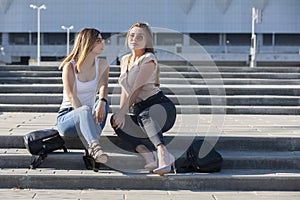 Two sexy girls sitting on a stairs. Outdoor fashion portrait