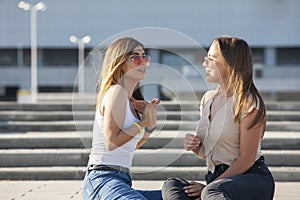 Two sexy girls sitting on a stairs. Outdoor fashion portrait