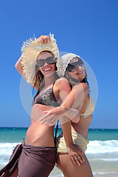 Two young girls or friends playing on a sunny beach on vaca